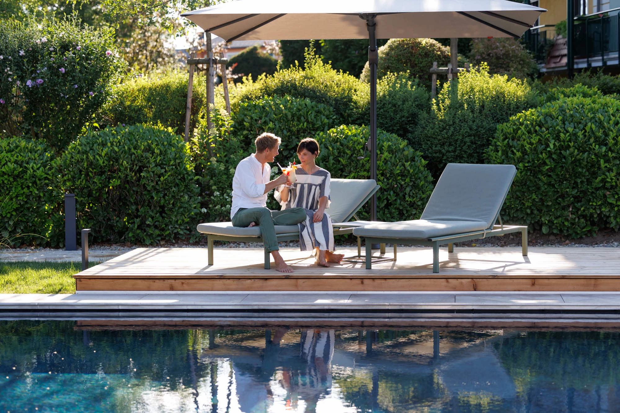 Weinlandhof Gamlitz, das Hotel an der südsteirischen Weinstraße. Ein mann und eine Frau sitzen mit einem Cocktail am Pool.