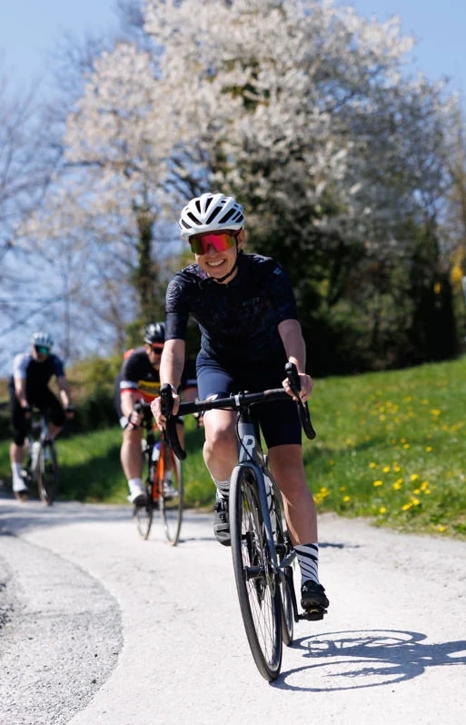 Frau in einer Gruppe Rennradfahrer fährt bergab